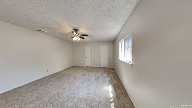 unfurnished bedroom with a textured ceiling, ceiling fan, visible vents, and light carpet