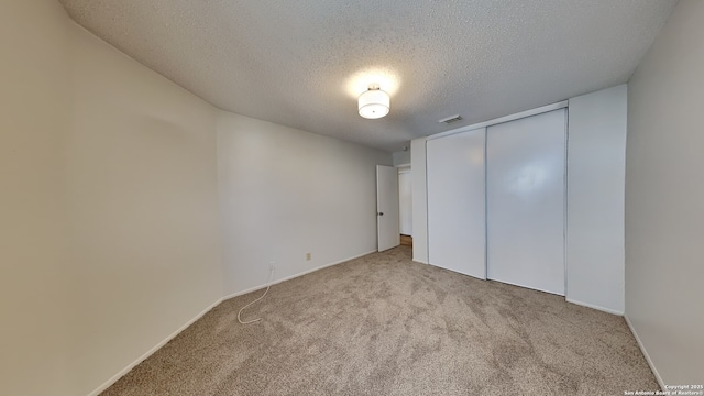 unfurnished bedroom with baseboards, visible vents, a closet, a textured ceiling, and carpet flooring