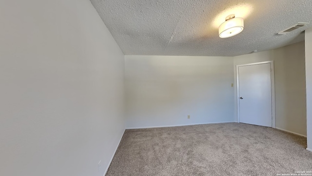 spare room with visible vents, a textured ceiling, and carpet floors