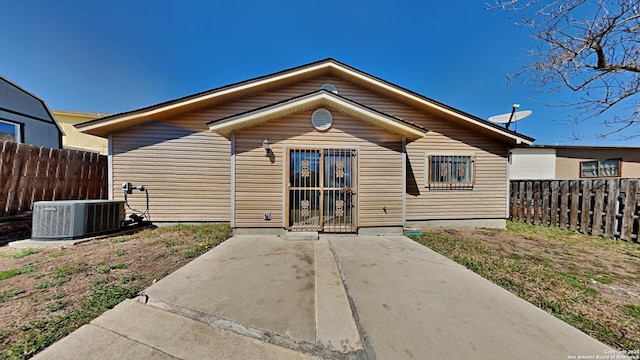 rear view of property featuring central air condition unit and fence