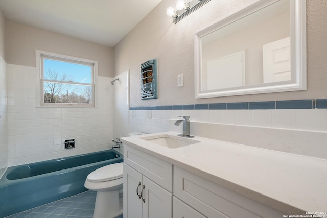 bathroom featuring tile patterned flooring, tile walls, washtub / shower combination, toilet, and vanity