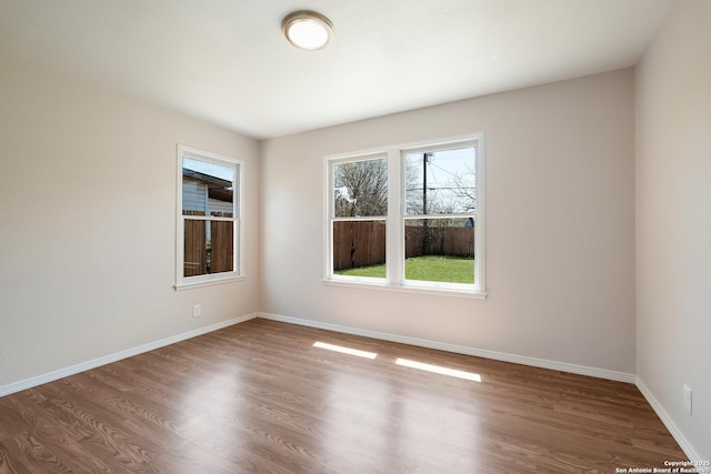 spare room with baseboards and wood finished floors