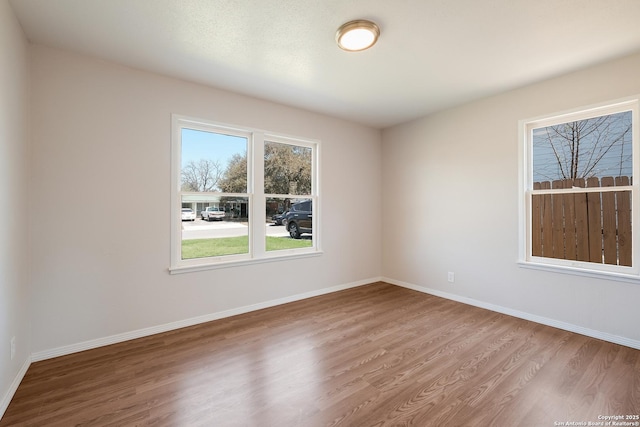 spare room with baseboards and wood finished floors