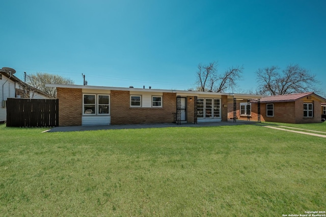 rear view of property with a yard, fence, and brick siding