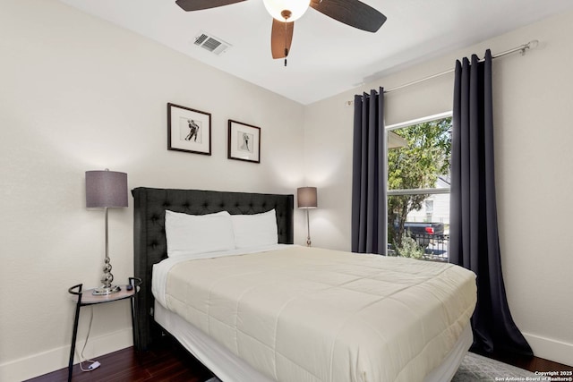 bedroom featuring visible vents, a ceiling fan, baseboards, and dark wood-style flooring