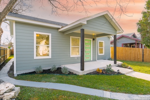 exterior space with a porch, a front lawn, and fence