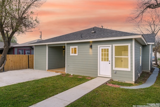 rear view of property featuring a lawn, a shingled roof, a patio, and fence