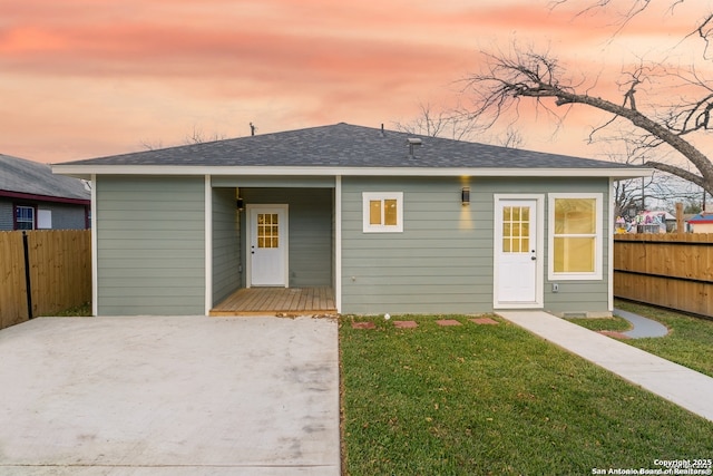 bungalow-style house featuring a lawn and fence