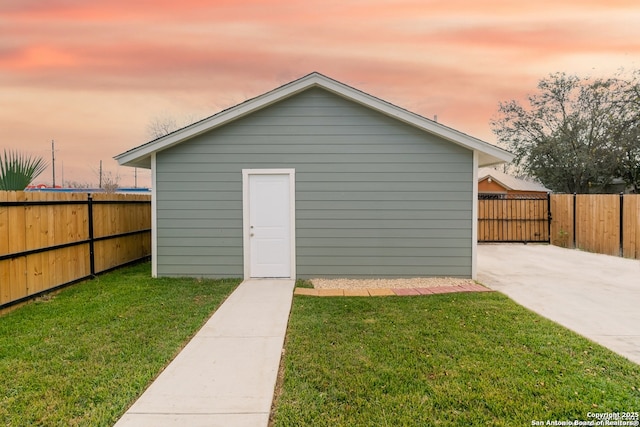 outdoor structure at dusk with an outbuilding, a yard, and a fenced backyard