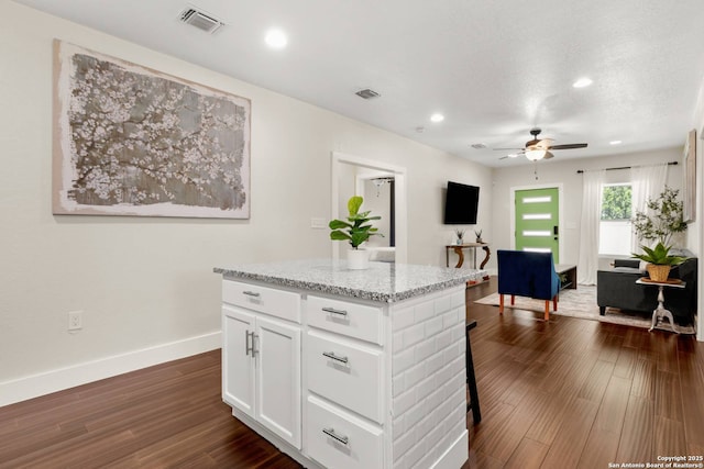 kitchen with visible vents, a ceiling fan, white cabinetry, baseboards, and dark wood-style flooring