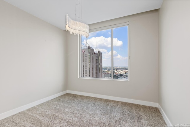 empty room featuring a view of city, plenty of natural light, carpet, and baseboards