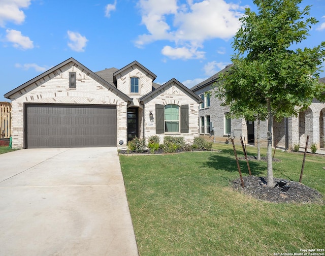 french country style house featuring brick siding, a garage, concrete driveway, and a front lawn