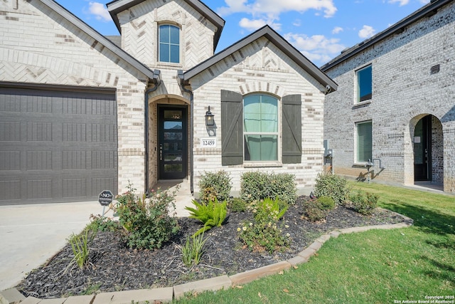 french provincial home with brick siding, a garage, and driveway