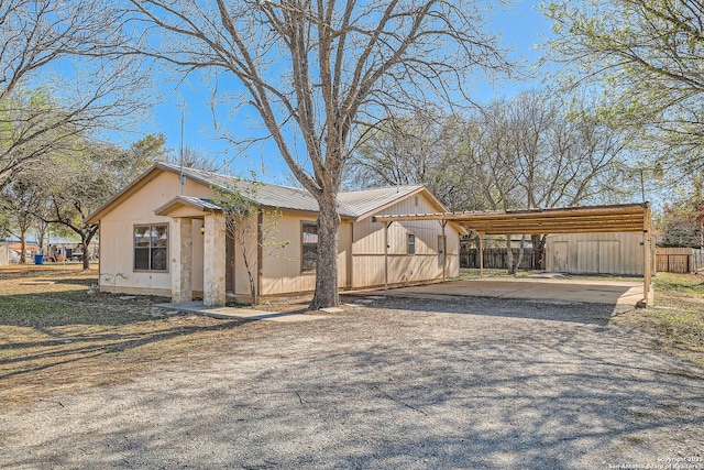 exterior space featuring a carport, driveway, metal roof, and fence