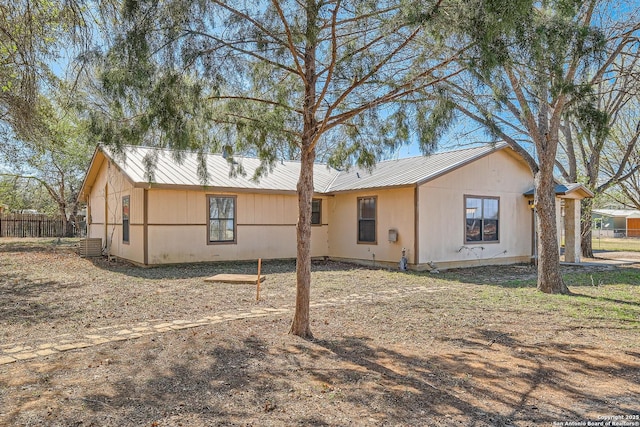 exterior space with metal roof, central AC, and fence