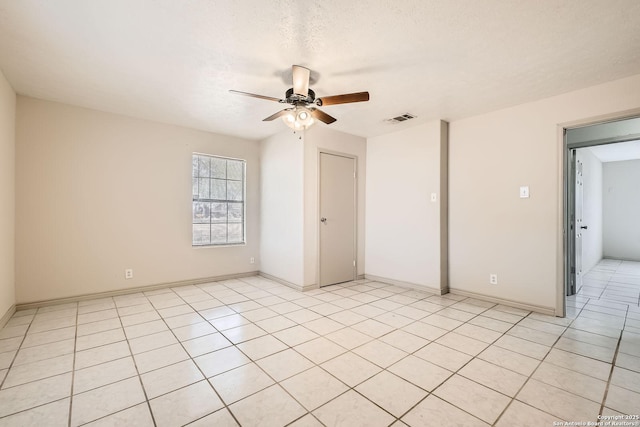 spare room with visible vents, baseboards, ceiling fan, light tile patterned floors, and a textured ceiling