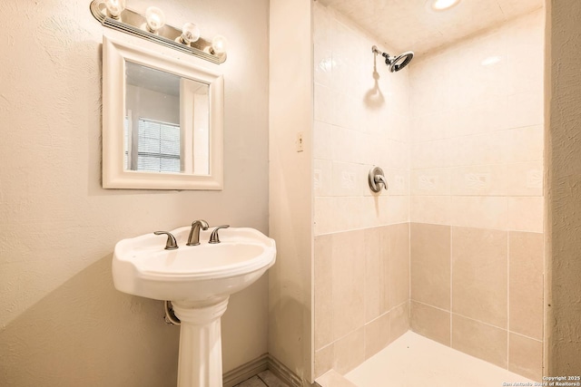 full bathroom with a sink and tiled shower