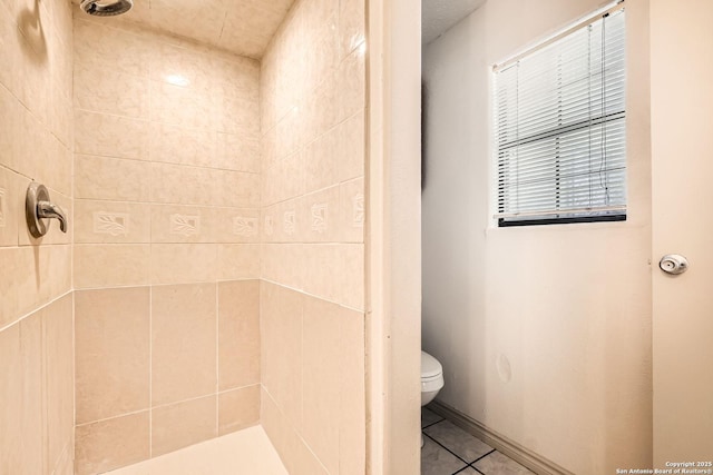 bathroom with tile patterned floors, tiled shower, and toilet