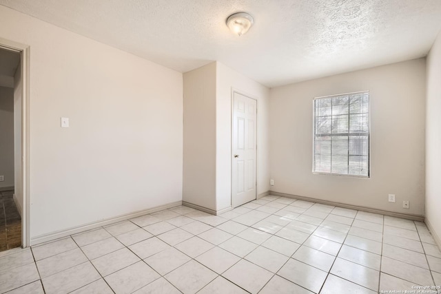 unfurnished bedroom with light tile patterned floors, baseboards, and a textured ceiling