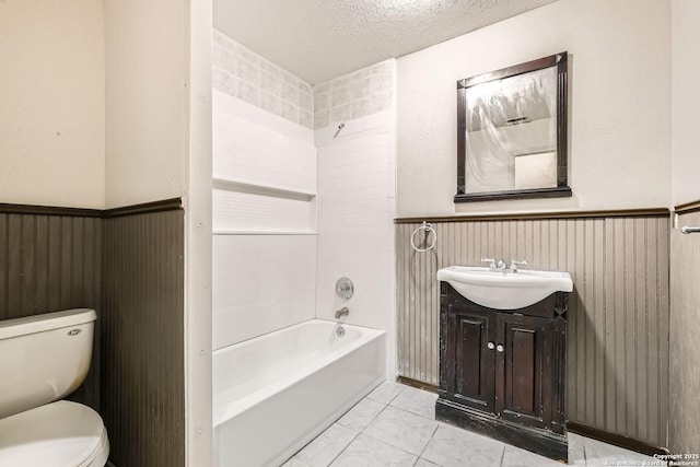 full bathroom with tile patterned floors, a wainscoted wall, toilet, a textured ceiling, and vanity