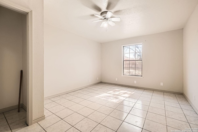 spare room with baseboards, ceiling fan, and light tile patterned flooring