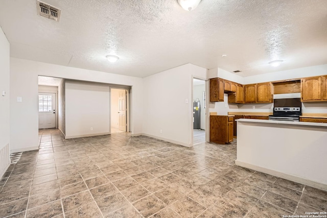 kitchen featuring visible vents, under cabinet range hood, stainless steel electric stove, brown cabinetry, and light countertops