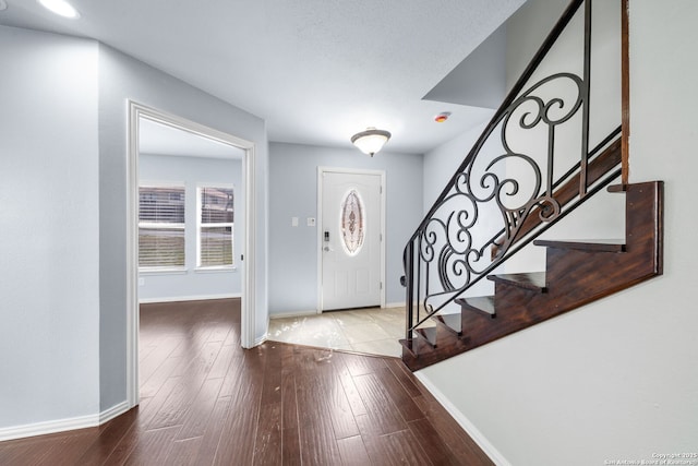 foyer featuring stairway, baseboards, and wood finished floors