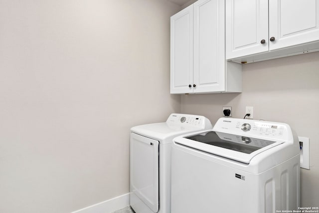 washroom featuring cabinet space, washer and dryer, and baseboards