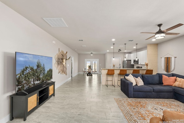 living room featuring visible vents, baseboards, and ceiling fan