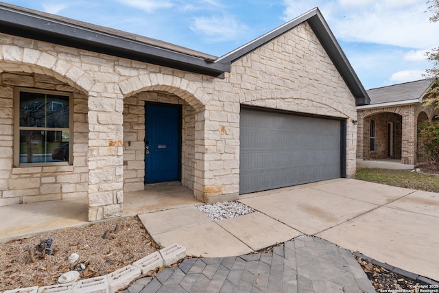 view of front of house with stone siding, driveway, and a garage