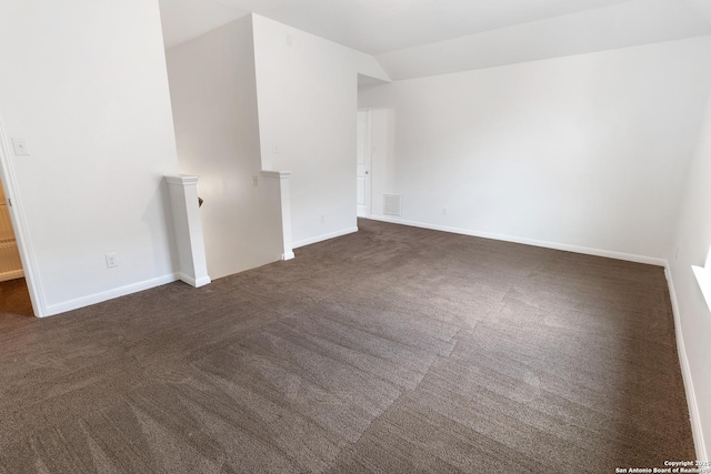 unfurnished room featuring visible vents, lofted ceiling, baseboards, and dark colored carpet