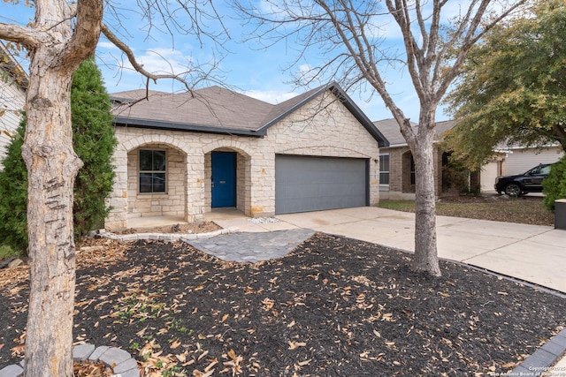 french country style house featuring driveway, stone siding, covered porch, roof with shingles, and a garage