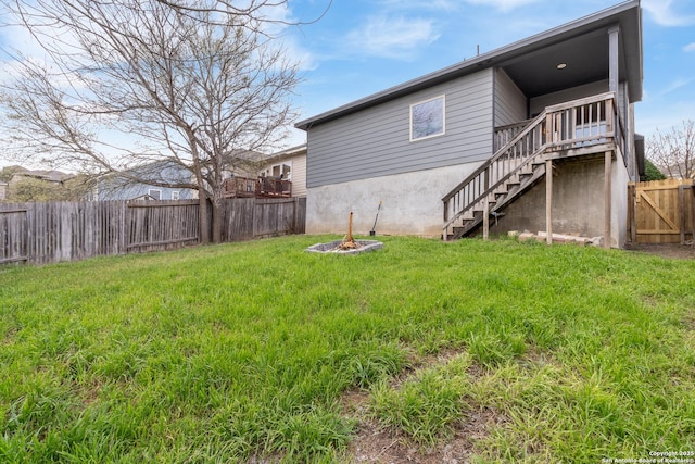 back of property featuring stairway, a fire pit, a fenced backyard, and a lawn