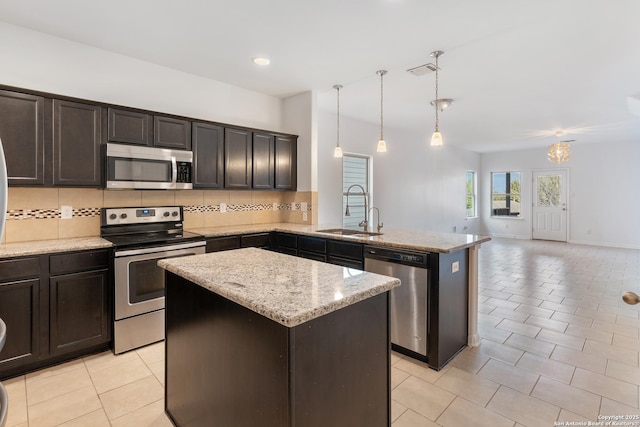 kitchen featuring visible vents, a kitchen island, a sink, decorative backsplash, and appliances with stainless steel finishes