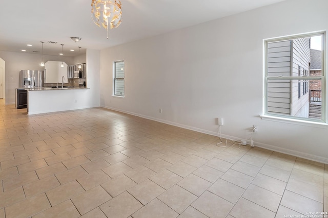 unfurnished living room with light tile patterned floors, baseboards, recessed lighting, a sink, and a chandelier