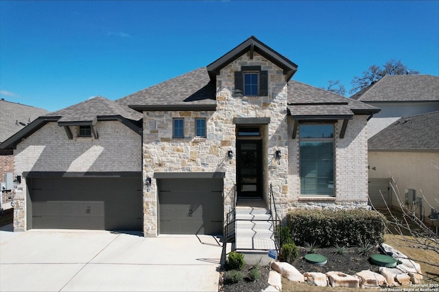 french provincial home with concrete driveway, stone siding, and a shingled roof