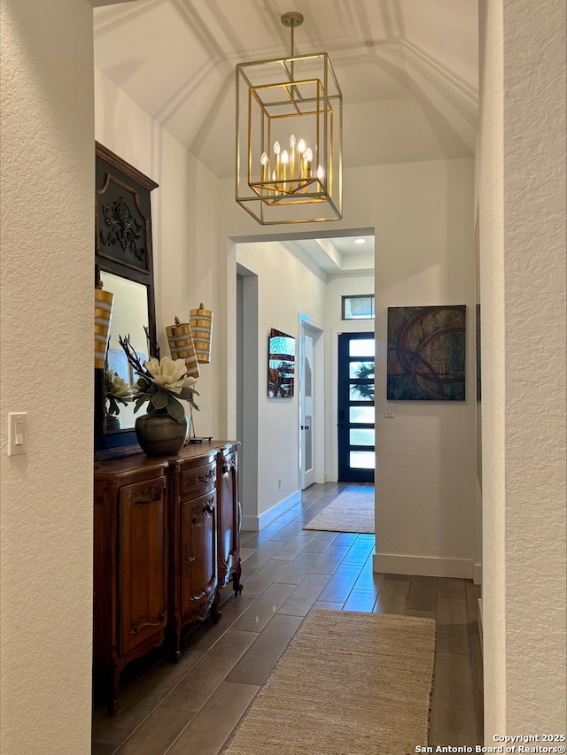 hall featuring an inviting chandelier and baseboards