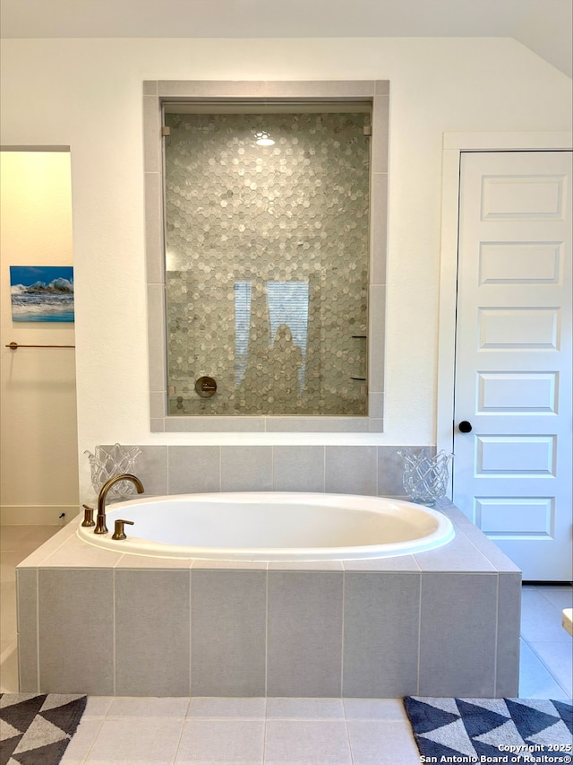 bathroom with tile patterned floors and a bath