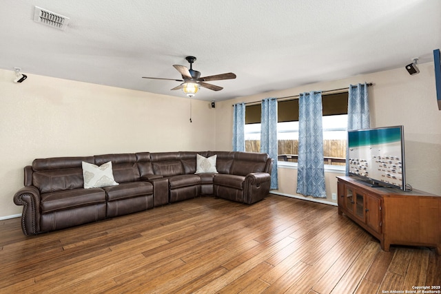 living room featuring visible vents, baseboards, hardwood / wood-style floors, a textured ceiling, and a ceiling fan