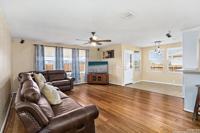 living area featuring visible vents, baseboards, a ceiling fan, and wood finished floors