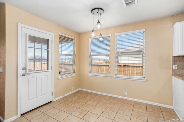 unfurnished dining area with light tile patterned flooring, visible vents, and baseboards