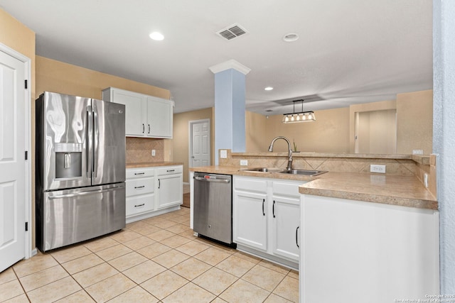 kitchen featuring light tile patterned floors, a sink, appliances with stainless steel finishes, white cabinetry, and tasteful backsplash