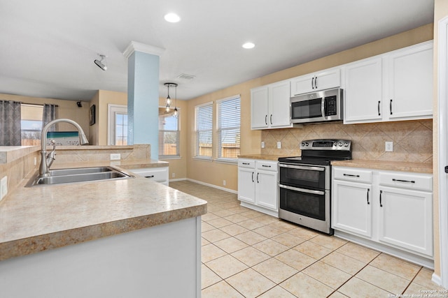 kitchen with light tile patterned flooring, a sink, stainless steel appliances, white cabinets, and tasteful backsplash