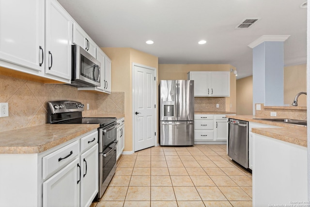 kitchen featuring visible vents, appliances with stainless steel finishes, light tile patterned flooring, white cabinetry, and a sink