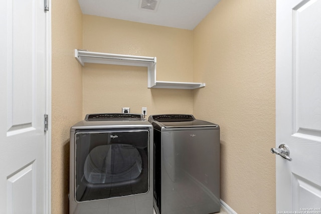 clothes washing area with visible vents, laundry area, and washing machine and clothes dryer