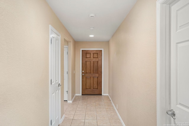 hallway with light tile patterned floors and baseboards