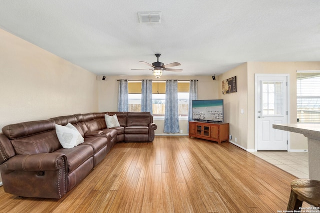 living area featuring visible vents, a healthy amount of sunlight, ceiling fan, and light wood finished floors