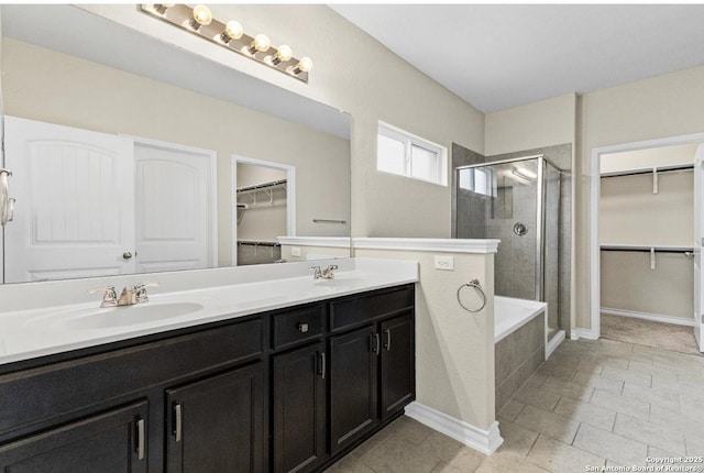 full bath featuring a sink, a walk in closet, a stall shower, and double vanity