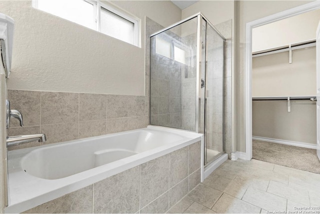 bathroom featuring a walk in closet, a shower stall, a garden tub, and tile patterned floors