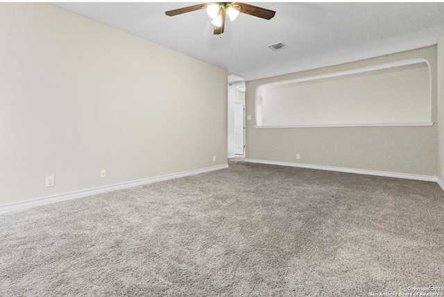 empty room with carpet, a ceiling fan, visible vents, and baseboards